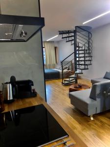 a living room with a couch and a spiral staircase at Apartmán Zara in Komárno