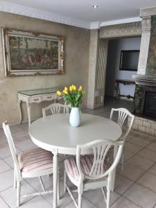 a white table and chairs with a vase of flowers on it at Columba Livia Guesthouse in Palanga