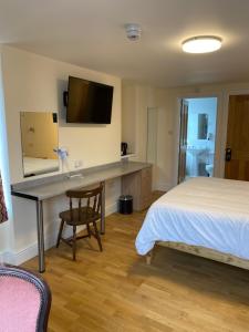 um quarto com uma secretária, uma cama e uma televisão em The Grand Harbour hotel em Ilfracombe