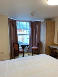 a room with a bed, chair, table and window at The Grand Harbour hotel in Ilfracombe