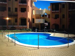 una gran piscina azul frente a algunos edificios en The Sandalia House en Olbia
