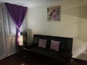 a living room with a black couch and purple curtains at Departamentos Amoblados R&M in Santiago