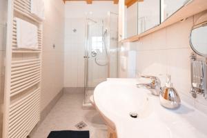 ein weißes Bad mit einem Waschbecken und einer Dusche in der Unterkunft Brugger Hof in Feldthurns