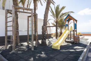a playground with a slide and palm trees at Listen the ROCKS in Costa Del Silencio