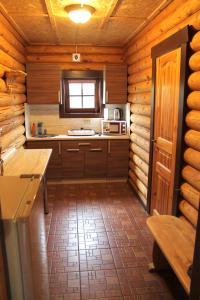 a kitchen in a log cabin with a window at Guest House Lyubyatovo in Pskov