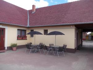 a patio with a table and chairs with umbrellas at Helga Apartman in Makó