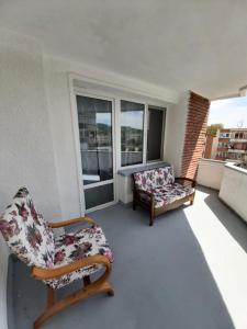 einen Balkon mit 2 Stühlen, einem Sofa und einem Fenster in der Unterkunft Chic Apartament in Deva