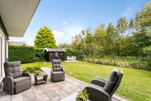 a patio with chairs and a table and a backyard at Prinsenhof 13 - Big, natural, fenced garden, dog friendly - not for companies in Ouddorp