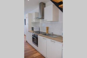 a kitchen with white cabinets and a sink at Maison à deux pas du centre ville de Ligny en Barrois in Ligny-en-Barrois