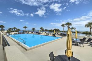 a pool at a resort with chairs and a umbrella at Waterfront Resort Condo with Private Beach and Pool in Hudson