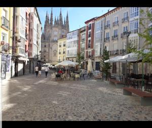 una calle de la ciudad con mesas y sillas y una iglesia en Precioso apartamento al lado de la Catedral, en Burgos