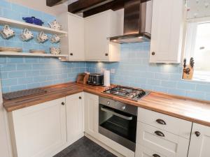 a kitchen with white cabinets and blue tiles at Afallon in Betws-y-coed