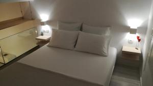 a bedroom with a white bed with pillows and lamps at Sixteen All Seasons House in Chania