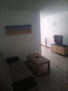 ein Wohnzimmer mit einem Sofa, einem Tisch und einem TV in der Unterkunft Piso Mesa del Mar in Tacoronte