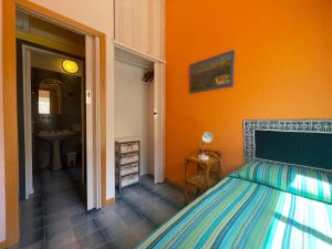 a bedroom with a bed and an orange wall at Villa Venere al Sauce - esclusiva villa sul mare in San Vito lo Capo