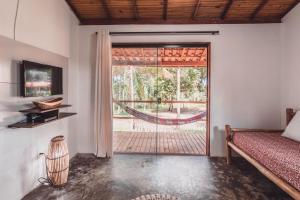 Habitación con cama y puerta corredera de cristal en Vila Piê, en Itacaré