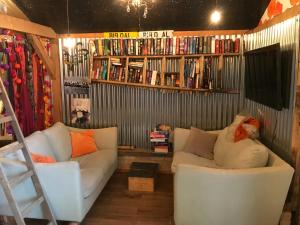 uma sala de estar com um sofá branco e prateleiras de livros em The Wackery! em Chiddingfold