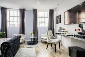a living room with a couch and chairs and a kitchen at Villare Leicester City Centre hotel in Leicester