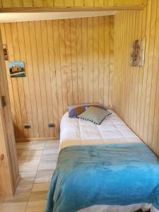 a bedroom with a bed in a wooden wall at Cabañas Rosner in Valdivia