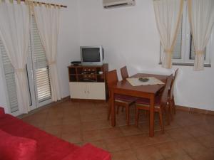 a dining room with a table and a tv at Apartment in Sukošan with balcony, air conditioning, WiFi (4941-1) in Sukošan