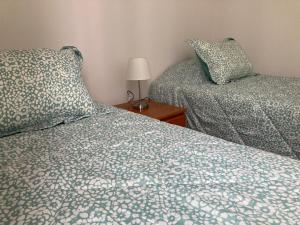 ein Schlafzimmer mit zwei Betten und einem Tisch mit Lampe in der Unterkunft BONITO DEPARTAMENTO A METROS DE AVENIDA DEL MAR in La Serena