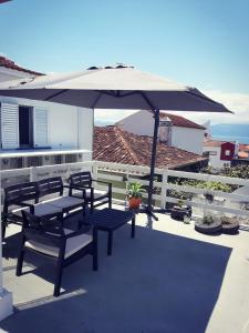 a patio with chairs and an umbrella on a balcony at Cantinho do Piano in Velas