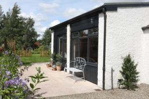 a white house with a bench in a garden at Garden Studio in Biggar in Biggar