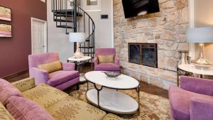 a living room with purple furniture and a stone fireplace at Best Western Plaza Inn in Pigeon Forge