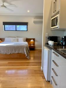 a bedroom with a bed and a kitchen with a sink at Aabi's at Byron in Byron Bay