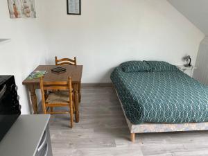 - une chambre avec un lit, une table et une chaise dans l'établissement Une escapade tranquille, proche de la plage !, à Dunkerque