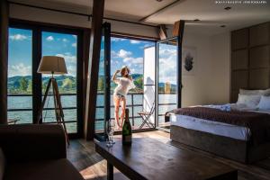 a woman standing in a bedroom with a view of the water at Boatel Copacabana in Veliko Gradište