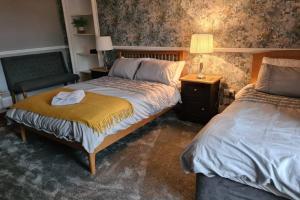 a bedroom with two beds and a chair and a lamp at North Coast Property - North Coast Cottage in Thurso