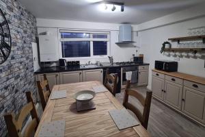 eine Küche mit einem Holztisch und Stühlen sowie eine Küche mit einem Fenster in der Unterkunft North Coast Property - North Coast Cottage in Thurso + 4 Fotos