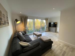 a living room with a black couch and a television at Penthouse Waterfront Apartment - St Neots in Saint Neots