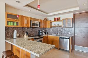 a kitchen with wooden cabinets and a granite counter top at Encanto Living Two Bedroom Unit by Kivoya in Puerto Peñasco