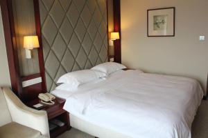 um quarto de hotel com uma cama branca e uma cadeira em Jinyuan Jinling Plaza Xuzhou em Xuzhou