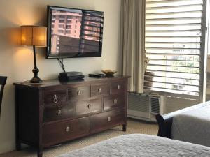 1 dormitorio con tocador y TV encima. en Tropical Studios at Marine Surf Waikiki - FREE PARKING - BEST LOCATION - FULL KITCHEN - SWIMMING POOL, en Honolulu