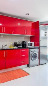 - une cuisine avec des placards rouges et un lave-linge dans l'établissement T3 Alex,moderno iluminado e amplo,excelente local, à Portimão