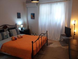 a bedroom with a bed with an orange blanket and a window at Nice apartments in the center of Athens! in Athens