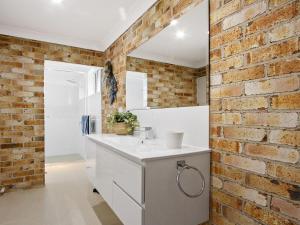 a bathroom with a brick wall and a white sink at Amersham in Callala Bay