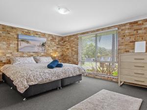 a bedroom with a bed and a brick wall at Amersham in Callala Bay