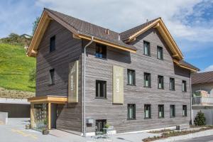 a large wooden building with a gambrel roof at kroneLODGE - Self-Check-In Hotel in Mosnang
