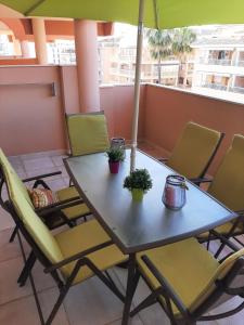 einen Tisch und Stühle auf einem Balkon mit Sonnenschirm in der Unterkunft Apartamento playa canet d'en Berenguer in Canet d'en Berenguer