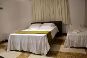 a hotel room with a bed and two tables at Pousada Maresias do Cumbuco in Cumbuco