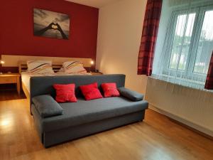 ein Schlafzimmer mit einem Sofa und einem Bett mit roten Kissen in der Unterkunft Gästehaus Ranftl in Unterlamm