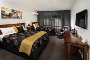 a hotel room with a bed and a desk and a desk at Addison Motor Inn in Shepparton