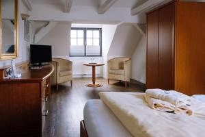Schlafzimmer mit einem Bett, einem Schreibtisch und einem TV in der Unterkunft SCHULZENS Brauerei & Hotel in Tangermünde