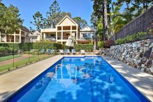 a large blue swimming pool in front of a house at Alderly Terrace in Noosa Heads