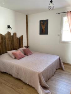 een slaapkamer met een groot bed met roze kussens bij Le cocon d’Emma in La Bresse