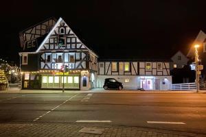 une voiture noire garée devant un bâtiment la nuit dans l'établissement Das alte Zollhäuschen, à Bad Laasphe